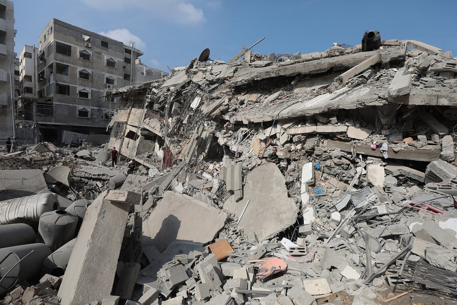 Street view of rubble piled several stories high between damaged buildings in Gaza.