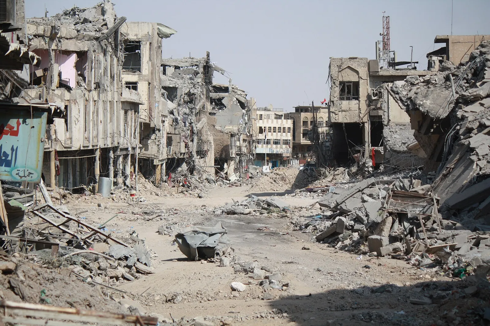 A street in Mosul's old city lined with collapsed and gutted buildings, rubble piled along both sides