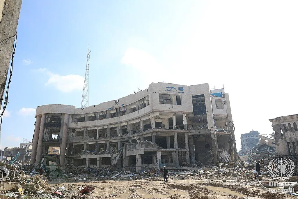 The destroyed UNRWA Sheikh Radwan health center — the building's concrete roof has collapsed onto twisted metal and medical supplies.